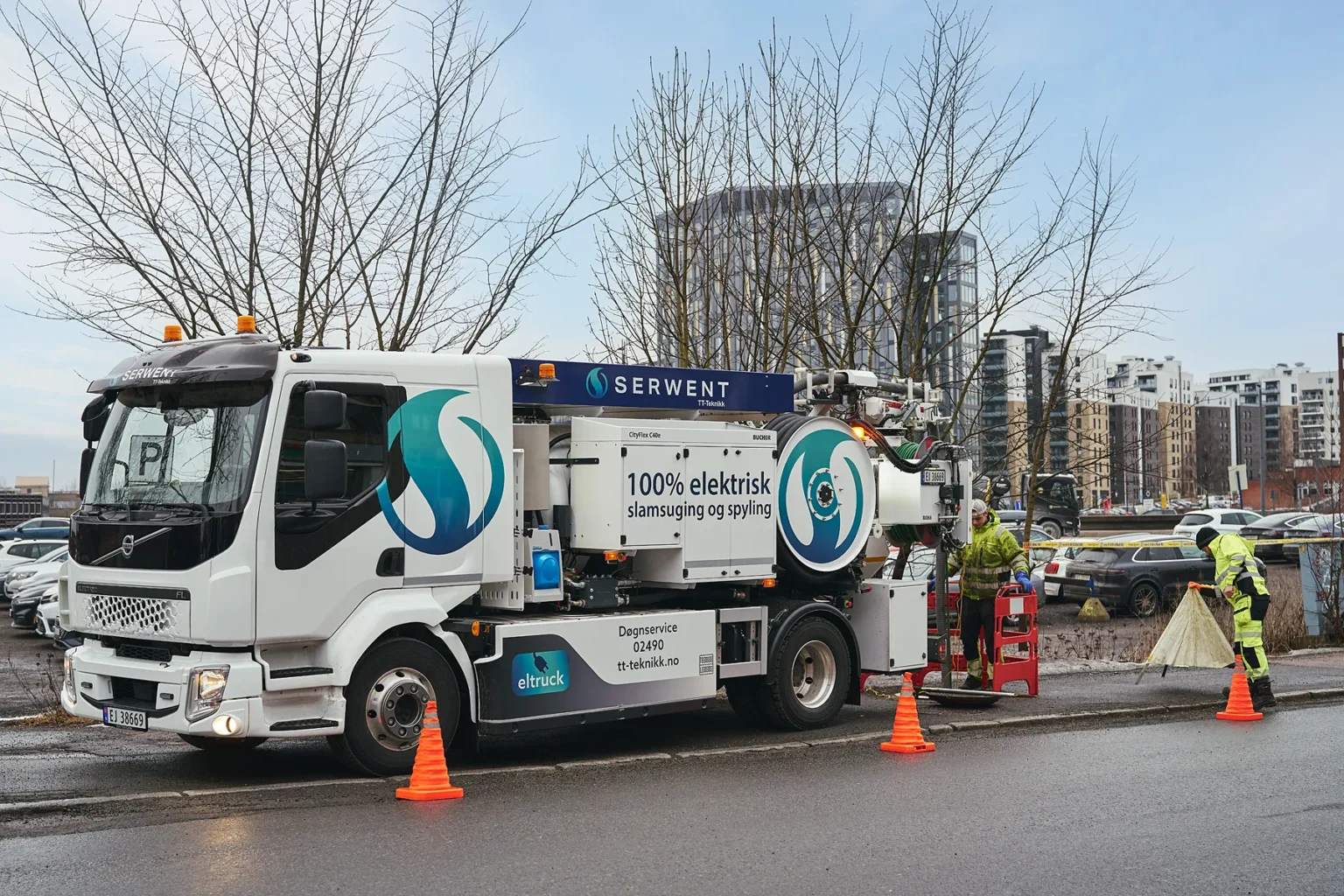 En hvit Serwent elektrisk bruksbil med "100% elektrisk" skrevet på siden står parkert ved en vei. To arbeidere i gult verneutstyr bruker utstyr nær oransje trafikkkjegler, med bybygninger og trær i bakgrunnen.