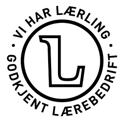 Et svart sirkulært emblem med stor L i midten, omgitt av den norske teksten VI HAR LÆRLING GODKJENT LÆREBEDRIFT, betyr sertifikat och tillstånd for godkjente lærebedrifter.